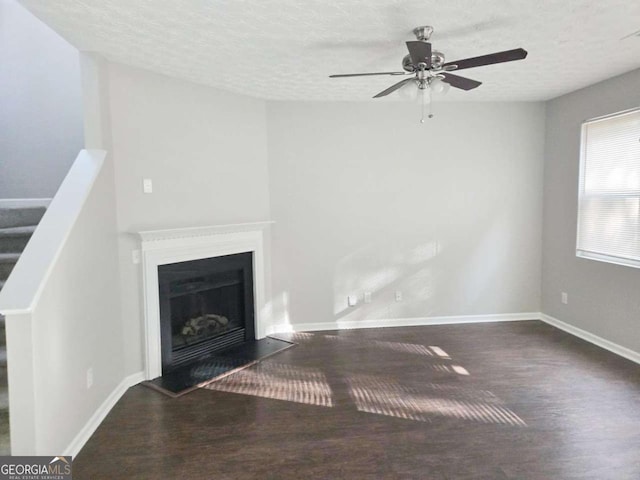 unfurnished living room featuring ceiling fan, dark hardwood / wood-style floors, and a textured ceiling