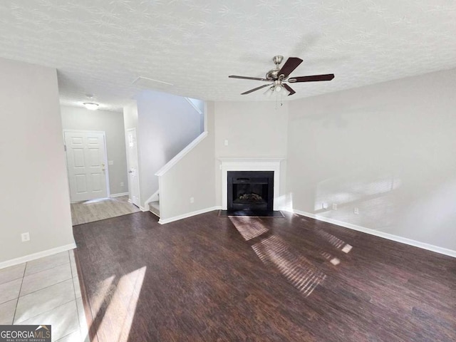 unfurnished living room featuring ceiling fan, hardwood / wood-style floors, and a textured ceiling