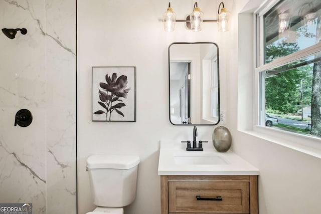 bathroom with tiled shower, vanity, and toilet