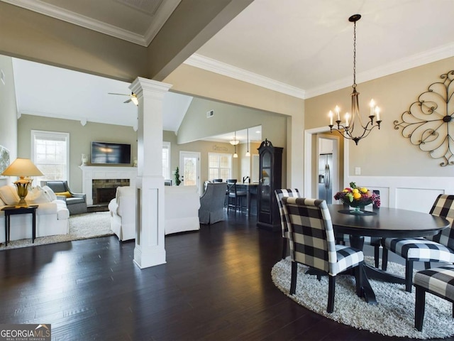 dining area with ornate columns, plenty of natural light, dark wood-type flooring, and ceiling fan with notable chandelier