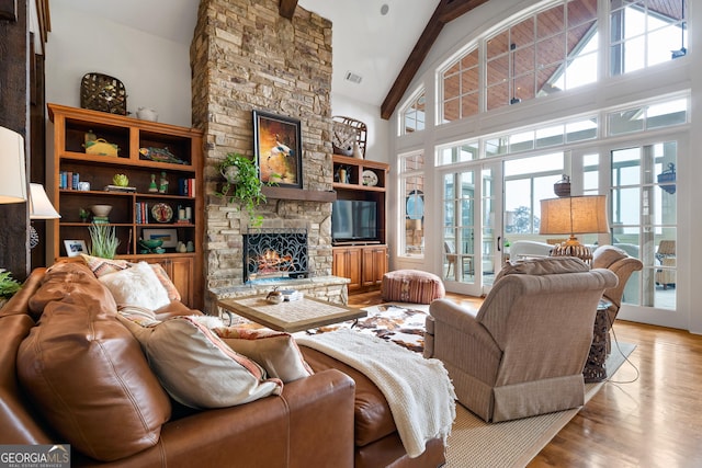 living room featuring light hardwood / wood-style flooring, high vaulted ceiling, a fireplace, french doors, and beamed ceiling