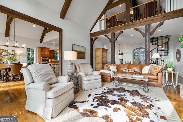 living room with light hardwood / wood-style floors, beam ceiling, a chandelier, and high vaulted ceiling