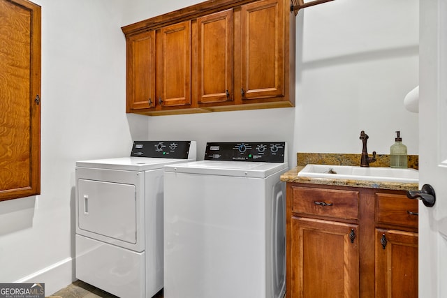 clothes washing area featuring cabinets, sink, and washer and dryer