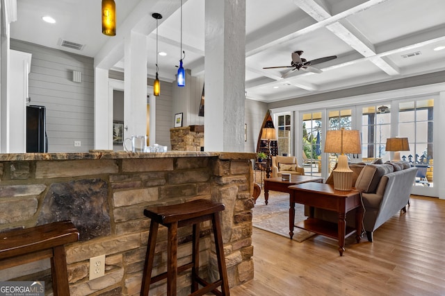 bar featuring black refrigerator, decorative light fixtures, coffered ceiling, and light hardwood / wood-style floors