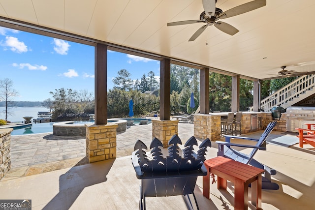 view of patio with a pool with hot tub, an outdoor kitchen, a water view, and exterior bar