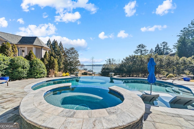 view of swimming pool with an in ground hot tub, a water view, and a patio area