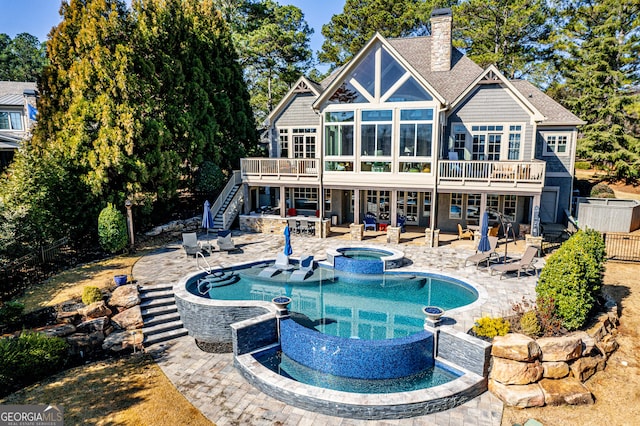 back of property featuring a patio, a sunroom, and a pool with hot tub