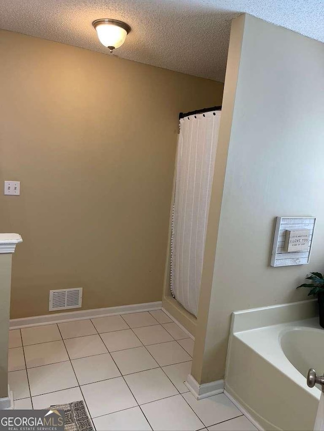 bathroom with tile patterned floors, a bath, and a textured ceiling