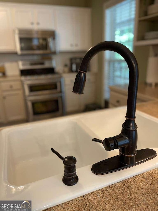 interior details with white cabinetry, sink, and range