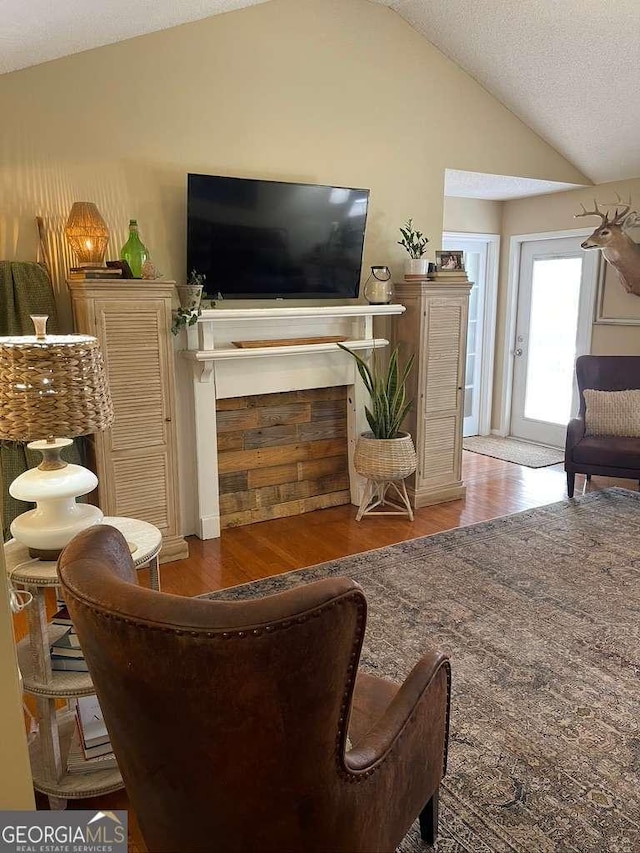 living room featuring hardwood / wood-style flooring, vaulted ceiling, and a textured ceiling