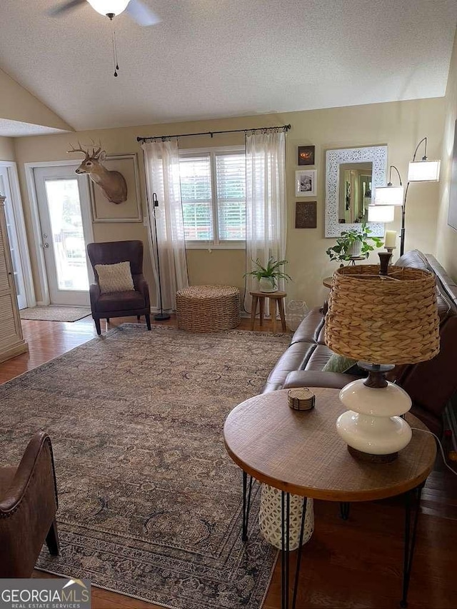 living room with ceiling fan, vaulted ceiling, and a textured ceiling