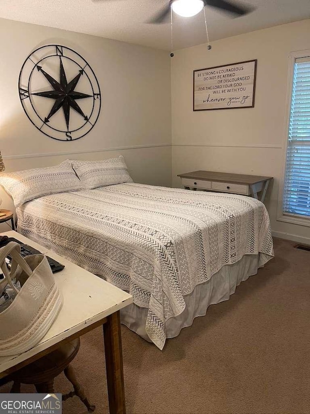 carpeted bedroom with ceiling fan and a textured ceiling