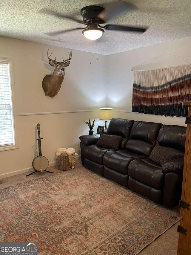 living room featuring ceiling fan, carpet floors, and a textured ceiling