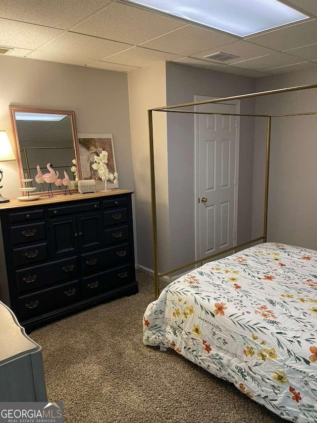 carpeted bedroom with a closet and a drop ceiling