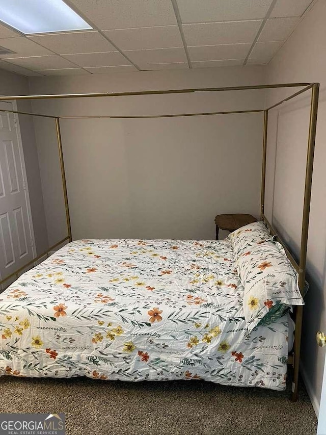 carpeted bedroom featuring a drop ceiling