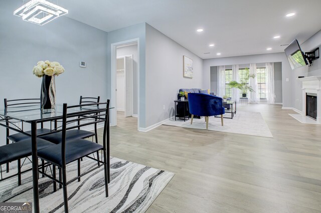 dining room with a premium fireplace and light wood-type flooring