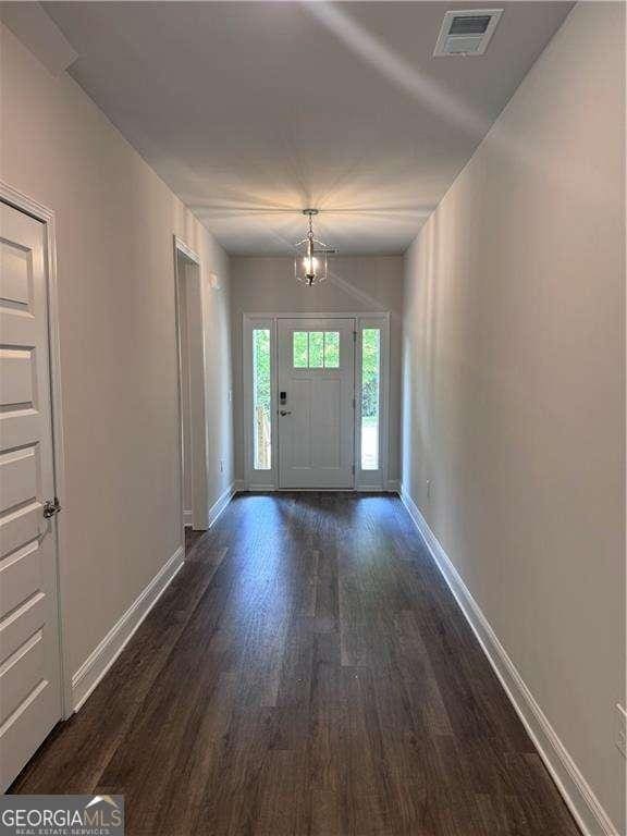 entrance foyer featuring an inviting chandelier and dark hardwood / wood-style flooring