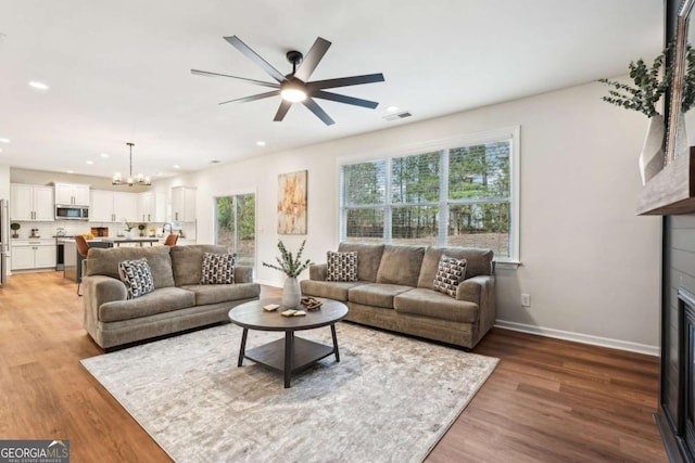 living room featuring hardwood / wood-style flooring and ceiling fan with notable chandelier