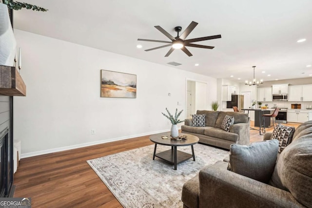 living room with dark hardwood / wood-style flooring and ceiling fan with notable chandelier