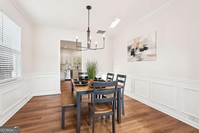 dining space with hardwood / wood-style flooring, ornamental molding, and a chandelier