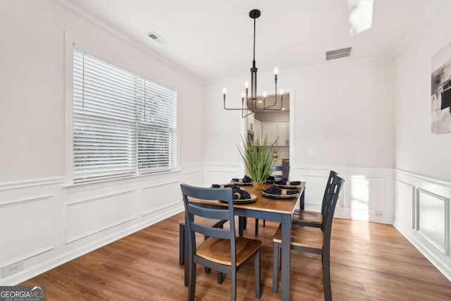 dining room featuring ornamental molding, hardwood / wood-style floors, and a chandelier