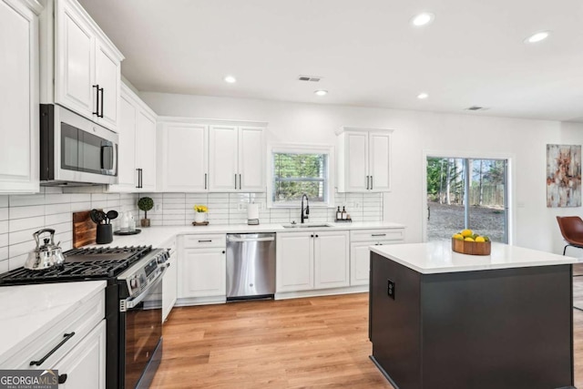 kitchen featuring white cabinetry, sink, light hardwood / wood-style floors, and appliances with stainless steel finishes