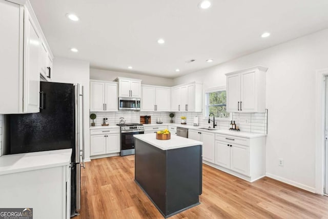 kitchen featuring stainless steel appliances, a kitchen island, and white cabinets