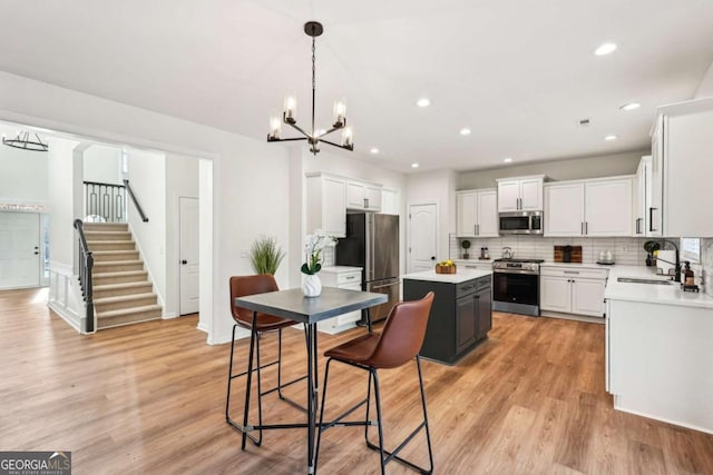 kitchen with appliances with stainless steel finishes, a center island, sink, and white cabinets