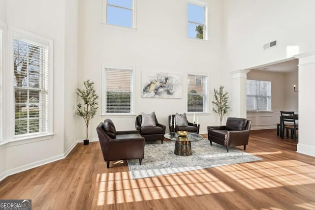 interior space with a wealth of natural light, light wood-type flooring, a high ceiling, and ornate columns