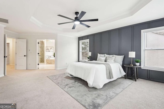 bedroom with crown molding, ceiling fan, ensuite bathroom, light carpet, and a raised ceiling