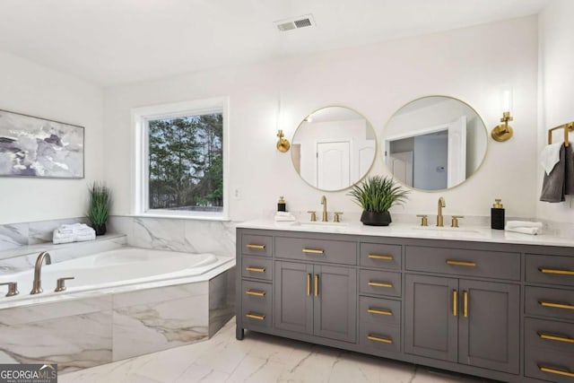 bathroom featuring a relaxing tiled tub and vanity