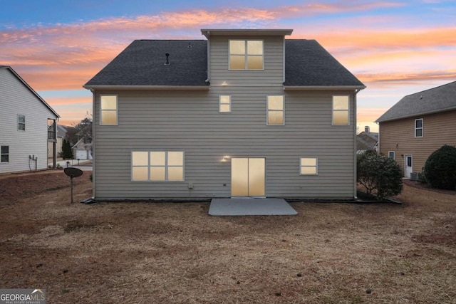 back house at dusk with a yard and a patio area