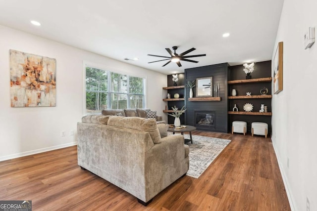 living room featuring hardwood / wood-style flooring, a large fireplace, and ceiling fan