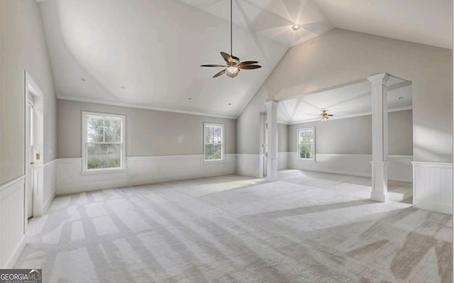 interior space featuring decorative columns, lofted ceiling, light colored carpet, ceiling fan, and crown molding