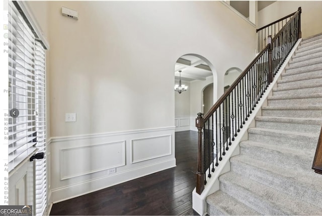 entrance foyer featuring coffered ceiling, an inviting chandelier, dark hardwood / wood-style floors, beamed ceiling, and a towering ceiling