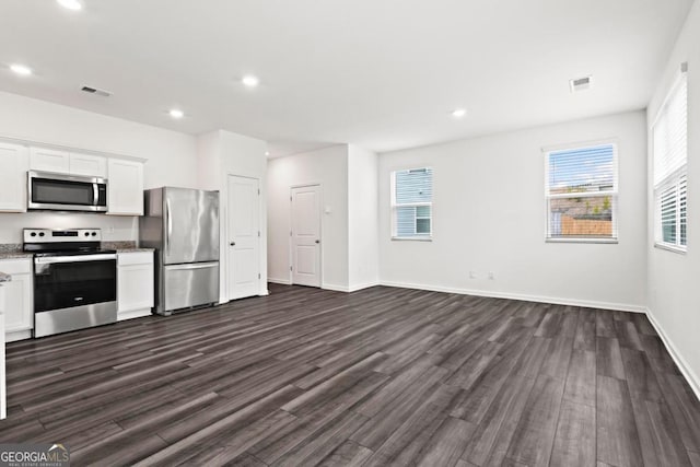 kitchen with white cabinetry, dark hardwood / wood-style flooring, a healthy amount of sunlight, and appliances with stainless steel finishes