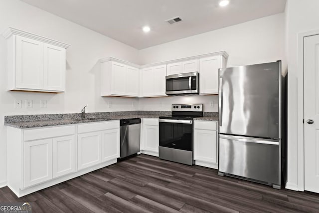 kitchen with dark hardwood / wood-style flooring, dark stone countertops, white cabinets, and appliances with stainless steel finishes