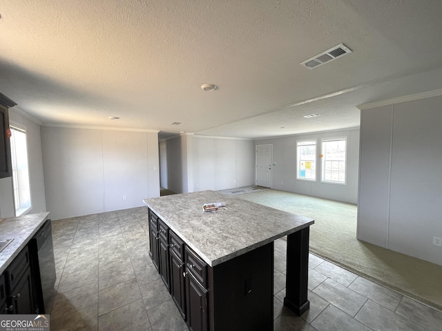 kitchen featuring a kitchen island, black dishwasher, ornamental molding, light carpet, and a textured ceiling