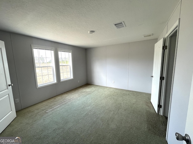 unfurnished room with carpet flooring and a textured ceiling