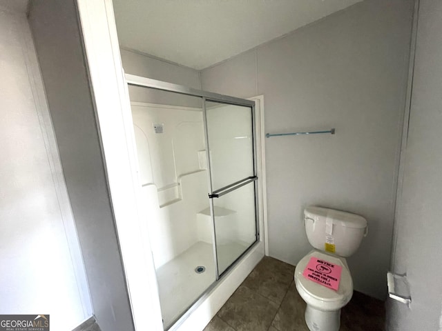 bathroom with tile patterned flooring, a shower with door, and toilet