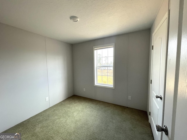 unfurnished room with a textured ceiling and carpet flooring