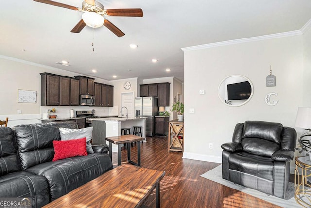 living room featuring dark wood-type flooring, ceiling fan, crown molding, and sink