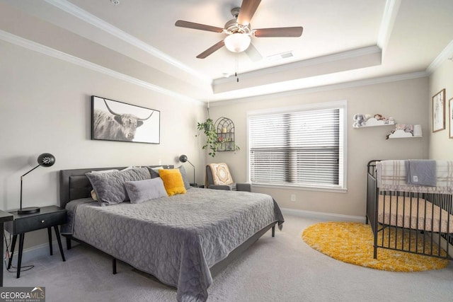 bedroom featuring a tray ceiling, carpet floors, ornamental molding, and ceiling fan