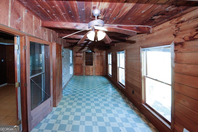 unfurnished sunroom with beam ceiling, ceiling fan, and wood ceiling