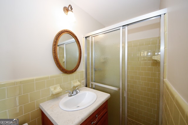 bathroom with vanity, a shower with door, and tile walls