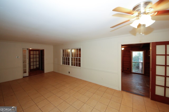 spare room with crown molding, light tile patterned floors, and ceiling fan