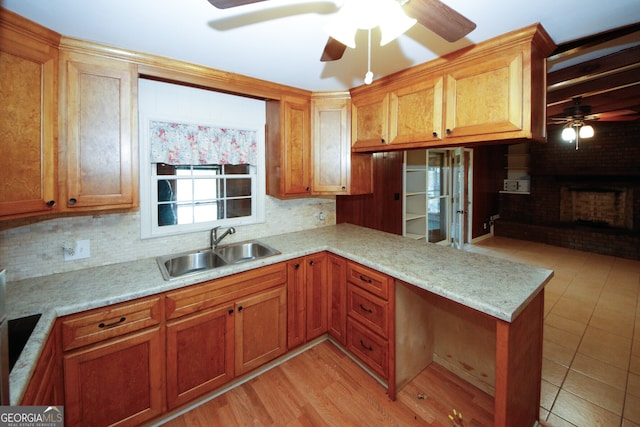 kitchen featuring sink, ceiling fan, tasteful backsplash, a fireplace, and kitchen peninsula