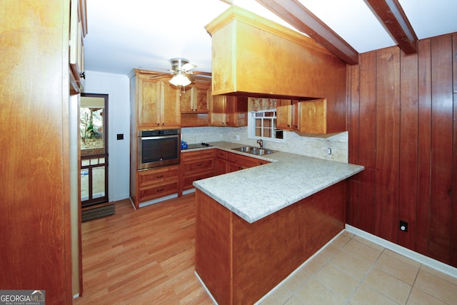 kitchen with beamed ceiling, tasteful backsplash, sink, oven, and kitchen peninsula