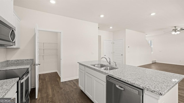 kitchen with appliances with stainless steel finishes, an island with sink, sink, white cabinets, and dark wood-type flooring