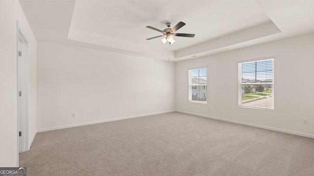 carpeted spare room featuring a raised ceiling and ceiling fan